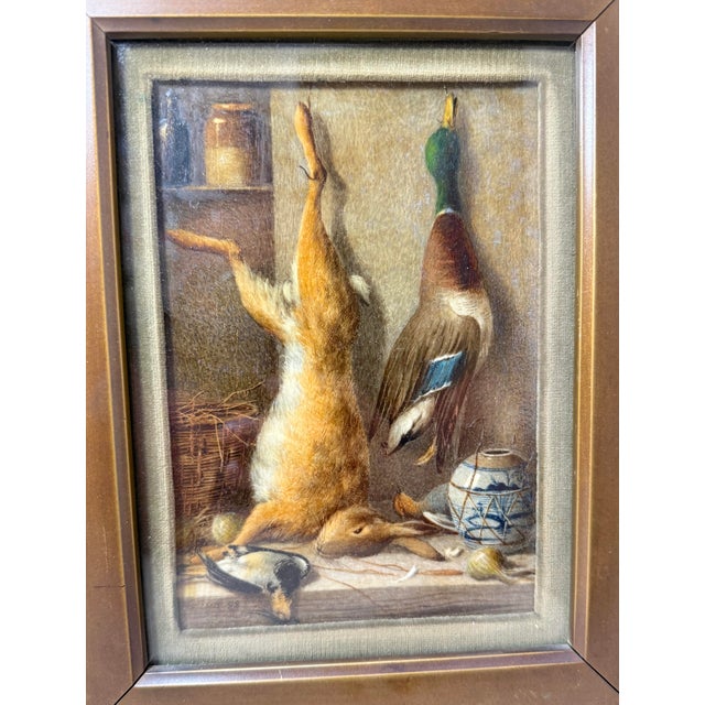 This antique oil painting by William Cruikshank from 1888 depicts a hunting scene with a rabbit, bird, and duck trophies...