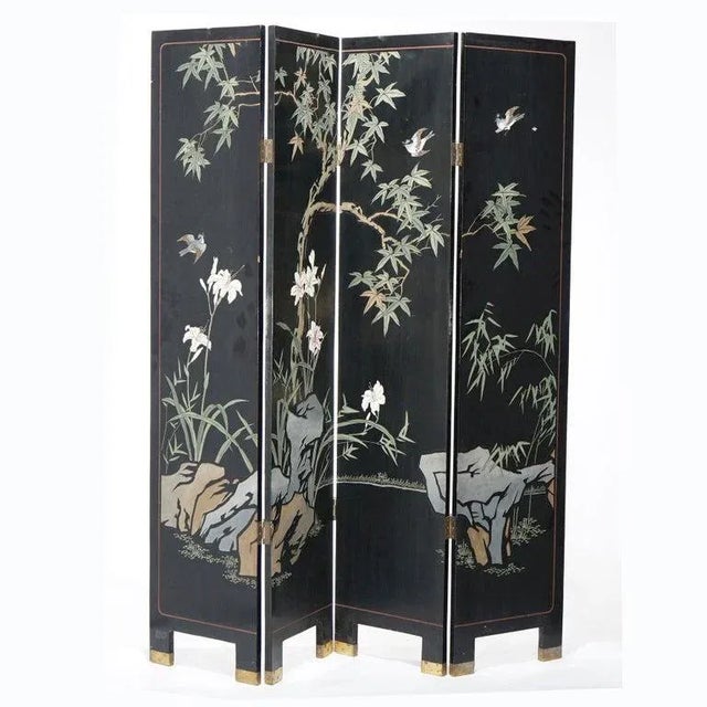 An Asian style screen offers four Chinoiserie decorated ebonized panels with landscape scene having garden with tree,...