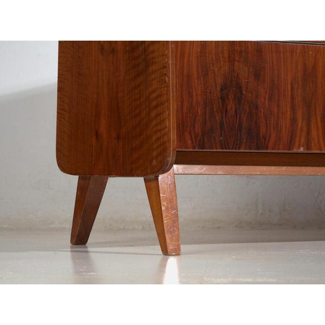 Mid-century sideboard veneered in walnut and raised on tapered legs, made in czechoslovakia around 1960. A mid-century...
