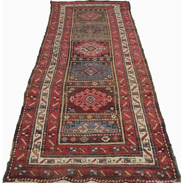 Handwoven Antique Persian Bakhtiari rug featuring a repetitive geometric panel design on a multi-colored field and ivory...
