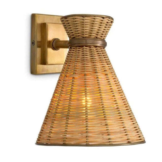 Pair of natural rattan wall lamp with vintage brass finish, designed in a contemporary style with a warm, textured...