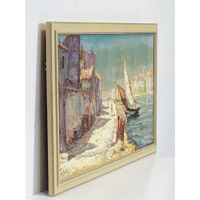 A fine French oil painting on canvas of a harbor scene, featuring a view of a sailboat and a picturesque town, signed M....