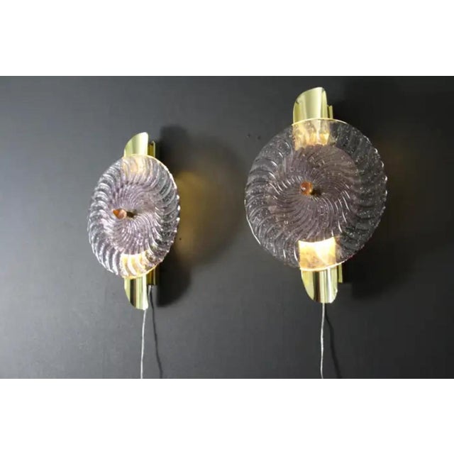 This striking pair of wall lamps is made of textured pink-purple Murano glass disk worked like a spiral swirled, put on a...