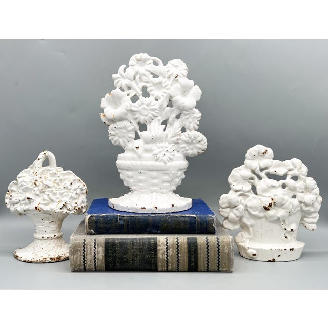 Delightful vintage set of three white cast floral door stops. Each features a dimensional basket or urn overflowing with...