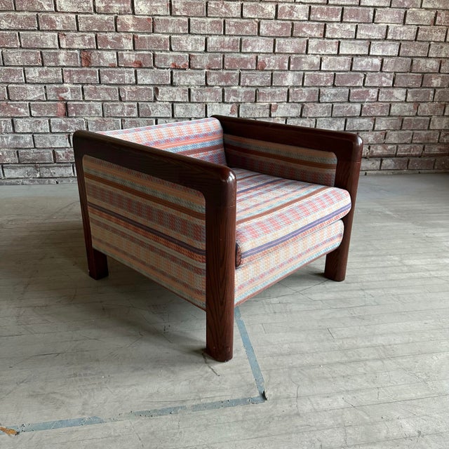 This cubed club chair has curved oak arm rests that waterfall right into the legs breaking up the structured lines and...