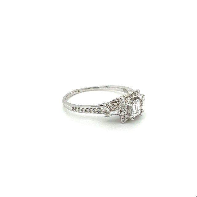 Vintage natural emerald, round, and baguette cut diamond engagement ring. The ring is made in 18k textured white gold and...