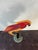 A vibrant vintage folk art kinetic sculpture depicting a stylized parrot perched in a graceful curved form. Crafted in...