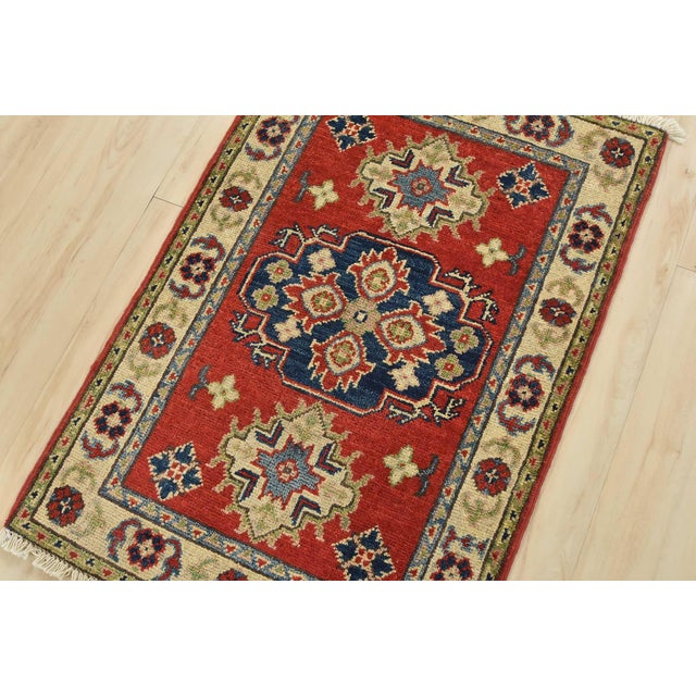 A tribal Caucasian Kazak rug hand-knotted with an all-wool pile on a cotton foundation. This oriental rug features a...