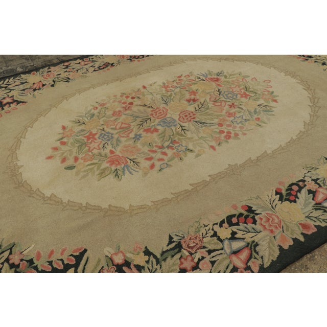 Handmade in wool, this 9x12 Antique Hooked rug, circa 1920-1929, features an elegant oval floral medallion framed by an...