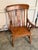 Antique walnut armchair featuring a carved backrest with a central decorative splat. The chair includes turned spindle arm...