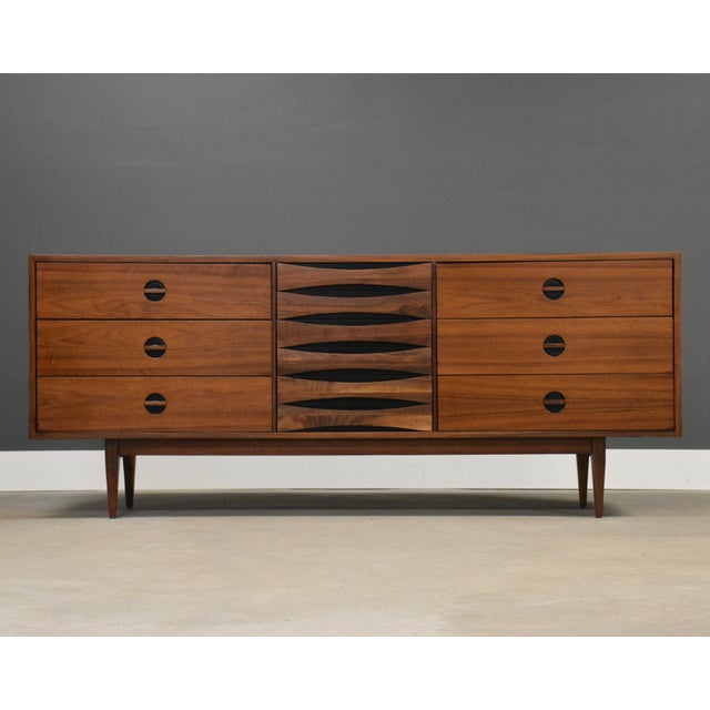 A mid century modern walnut dresser made by West Michigan Furniture with black inset pulls in the style of Arne Vodder....