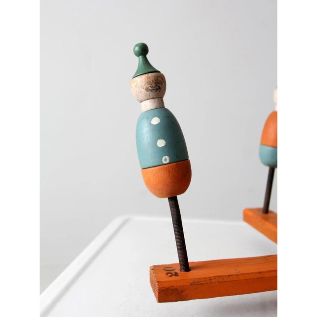 This is an antique ring toss carnival game. The wooden toy features four colorful clown spring "pegs" that set atop a...