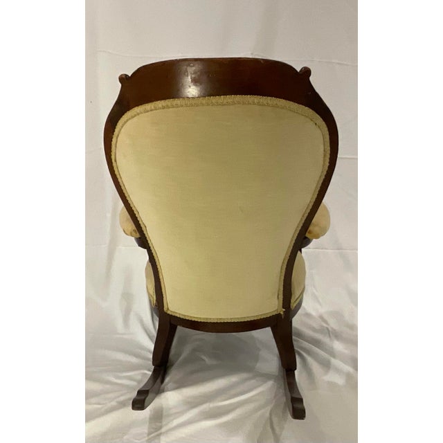 Lovely, petite antique rocking chair with scroll arms. Circa 1910. Wood frame with green upholstery. This is a charming...