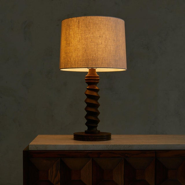 A French table lamp from the 1950s, attributed to Charles Dudouyt. The turned wooden base rises in a spiraling rhythm of...