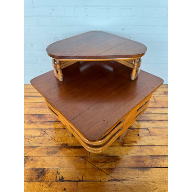 Two-tiered rattan side table, design of which is attributed to Paul Frankl. This piece is in good vintage condition and...