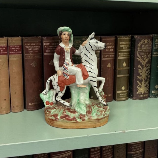 A highly decorative English pottery figure in the Staffordshire tradition, depicting a young rider seated atop a stylized...