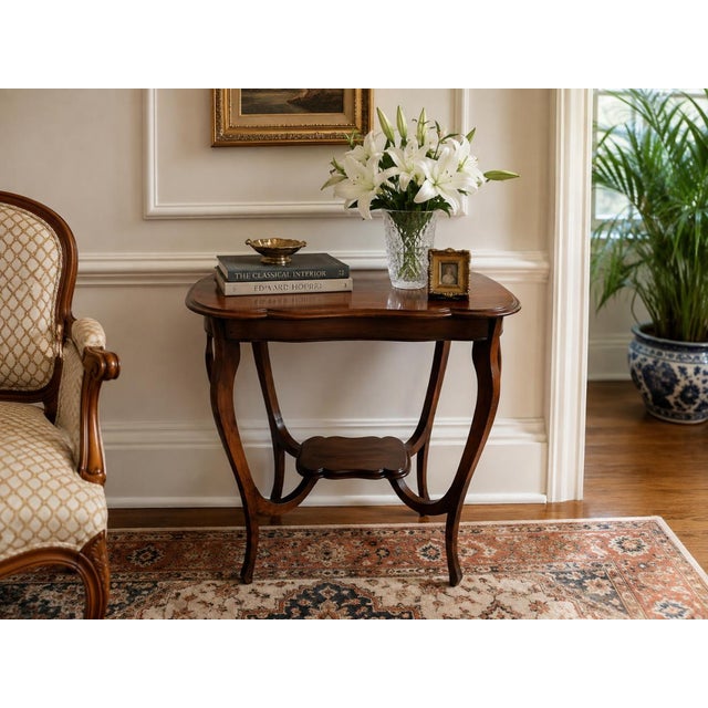Elegant antique mahogany accent table featuring a gracefully scalloped serpentine top, slender cabriole legs, and curved...