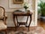 Elegant antique mahogany accent table featuring a gracefully scalloped serpentine top, slender cabriole legs, and curved...