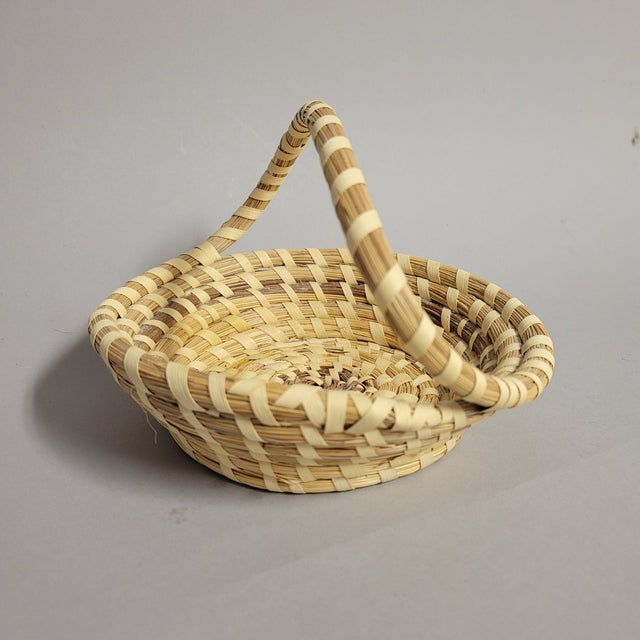 An elegant Gullah sweetgrass basket from Charleston, South Carolina, measuring 6.5" in diameter and 5" high including the...
