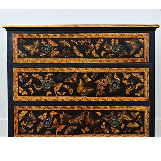 An English pine chest of drawers has been recently updated with new paint of ebonized effect and pasted découpage moths....