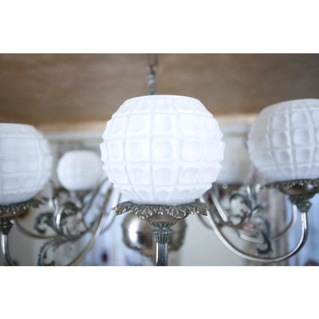 Eight-arm chandelier made of white brass. The body of the chandelier is decorated with plant motifs. Shades made of white...