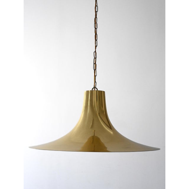 Brass chandelier with a white chrome interior, made between the 1960s and 1970s, with a wide, flowing silhouette. Vintage...
