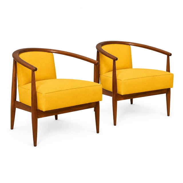 Modern mid century lounge chairs done in a yellow chenille upholstery. The chairs have a walnut finish. The chairs are...