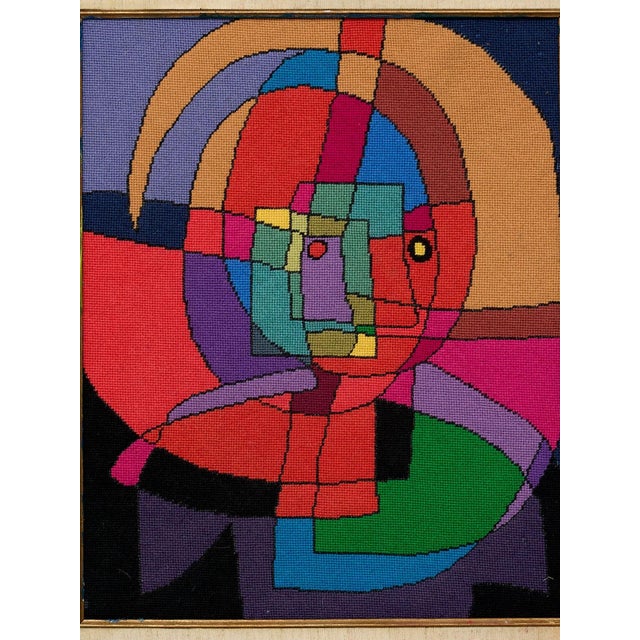 A striking vintage needlepoint artwork featuring an abstract Cubist-inspired portrait composed of bold geometric shapes...