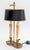 Brass Two-Light table lamp with candlestick iconic design, shell form handle and black tole shade. 16" H x 7.25" W x 4.75"...