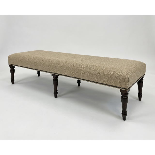 This custom-made bench features a tailored silhouette with subtle, textural upholstery in a neutral camel tone. Accented...