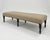 This custom-made bench features a tailored silhouette with subtle, textural upholstery in a neutral camel tone. Accented...