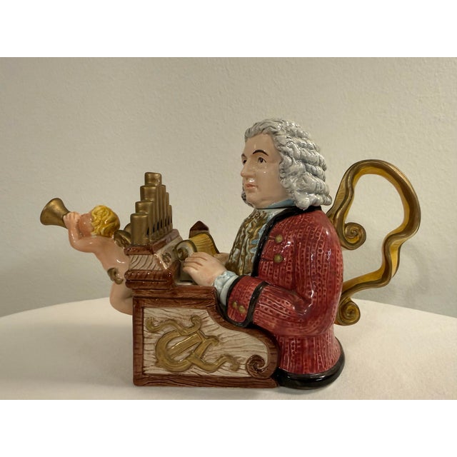 An eye-catching vintage ceramic figural teapot featuring the legendary composer Johann Sebastian Bach seated at an ornate...