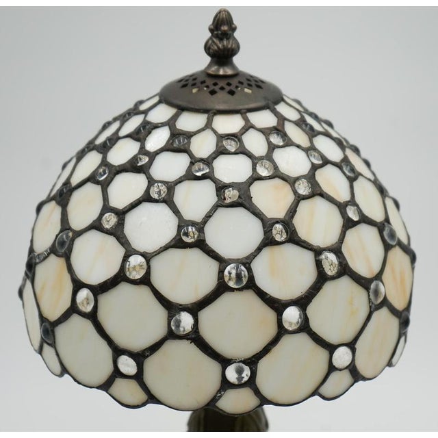 A charming vintage Tiffany-style table lamp featuring a beautiful white stained glass shade that casts a soft, warm glow...