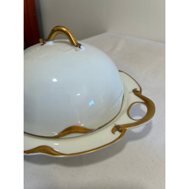 This elegant domed covered dish is by Haviland & Co., Limoges, France, featuring a sculptural gold gilt handle atop the...