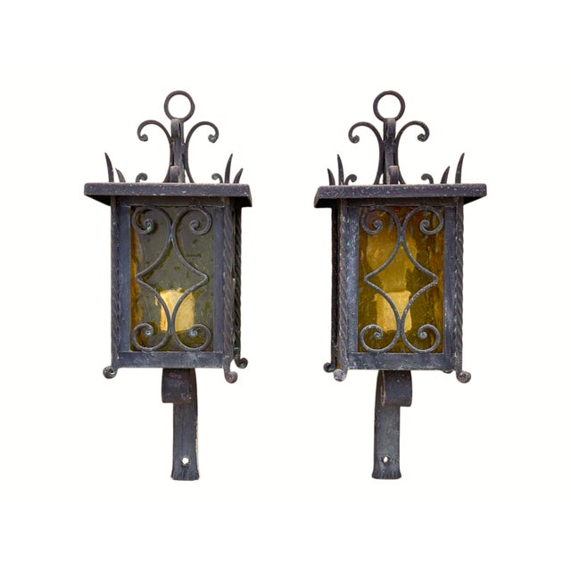Pair of Italian exterior wall lanterns circa 1950. Amber glass panels are secured with scrolled and twisted wrought iron...