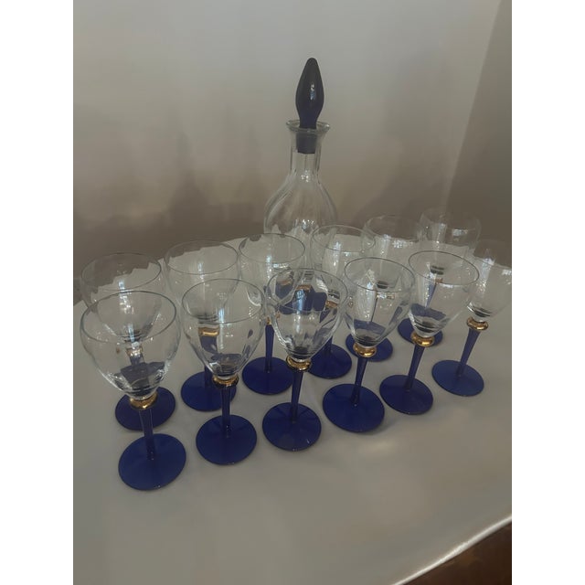 Striking set of twelve vintage stemmed glasses with a decanter featuring clear bowls with subtle vertical optic detailing,...
