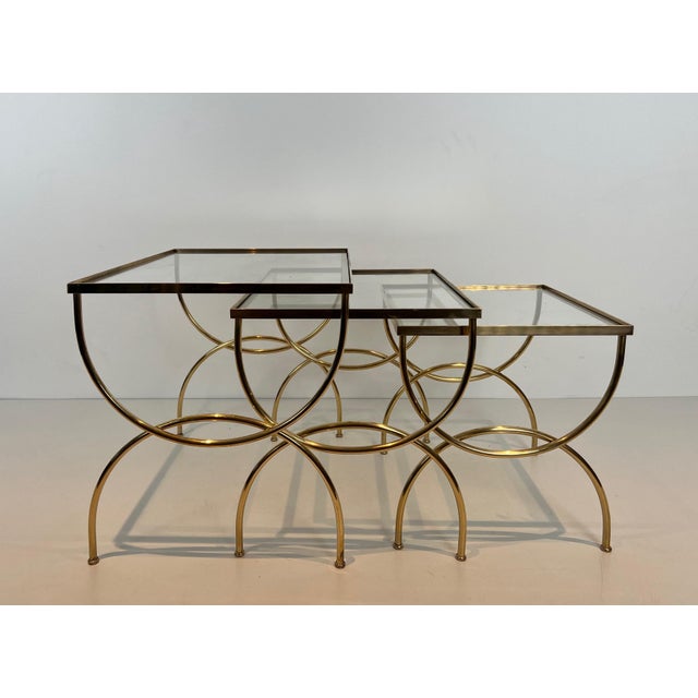 This beautiful neoclassical style nesting table with an arched base is made of brass with clear glass shelves. It is a...