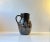 A dark brown glazed stone jug with agressive brutalist pattern finished with white glaze. It was made during the 1950s at...