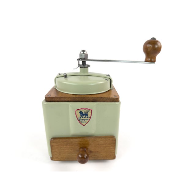 A charming mid-century French manual coffee grinder by Peugeot Frères, featuring a soft sage-green painted metal body,...