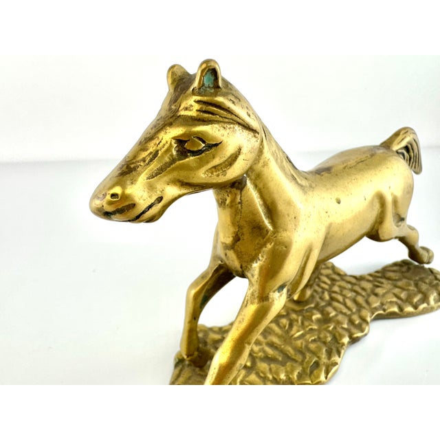 A sculptural mid-century brass horse frozen in mid-stride, this vintage figurine captures the energy of movement with...