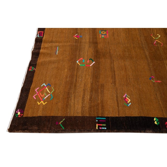 Beautiful vintage Turkish hand-knotted wool rug with a tan field. This Turkish rug has brown frame and multi-color accents...