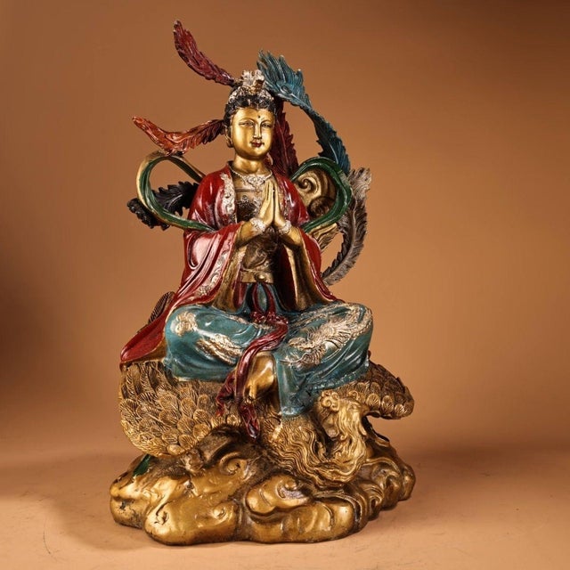 A striking cast bronze statue depicting a goddess figure seated atop a phoenix and cloud form base. The sculpture features...