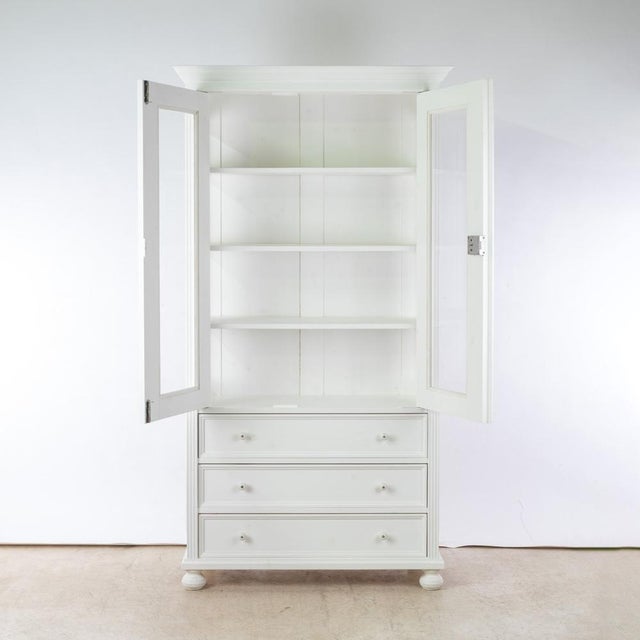 The display cabinet combines classic elegance with practical functionality. Made from solid pine and painted white, it...
