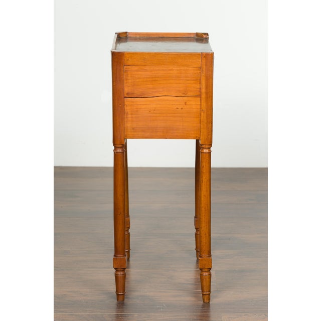A petite French walnut side table from the 19th century, with marble top and cylindrical legs. Created in France during...