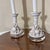 A pair of white glazed ceramic candlestick-style table lamps featuring relief details of fruit clusters (pomegranates,...