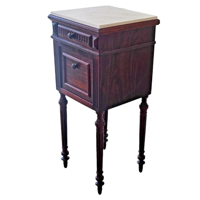 Bring understated French elegance into your home with this charming 1920s antique stone top nightstand, crafted in rich...