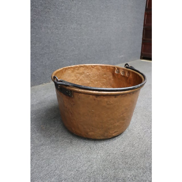 Antique hand-hammered copper apple butter kettle featuring a warm, naturally aged patina and a hand-forged wrought iron...