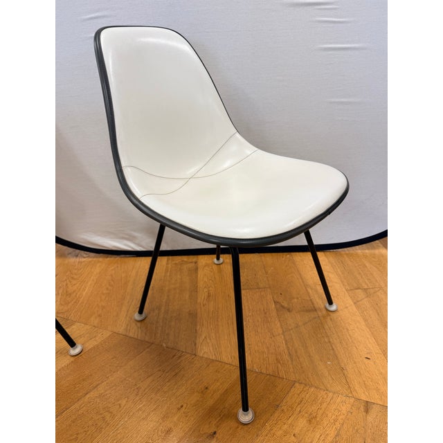 A striking set of four vintage Herman Miller molded shell side chairs featuring original white upholstery with contrasting...