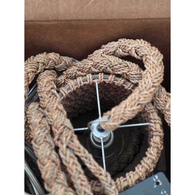 A rattan frame embellished by abaca rope and held in place on a wall bracket, it loops the cord around while a coil-weave...