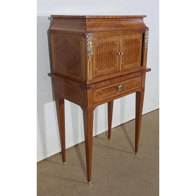Small cabinet with rounded and recessed sides. It is composed of two curtained doors, sliding on the sides, with bronze...